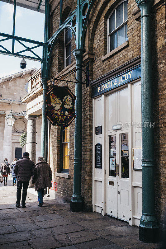 英国伦敦考文特花园市场Punch & Judy酒吧关门后的招牌上，行人走过。